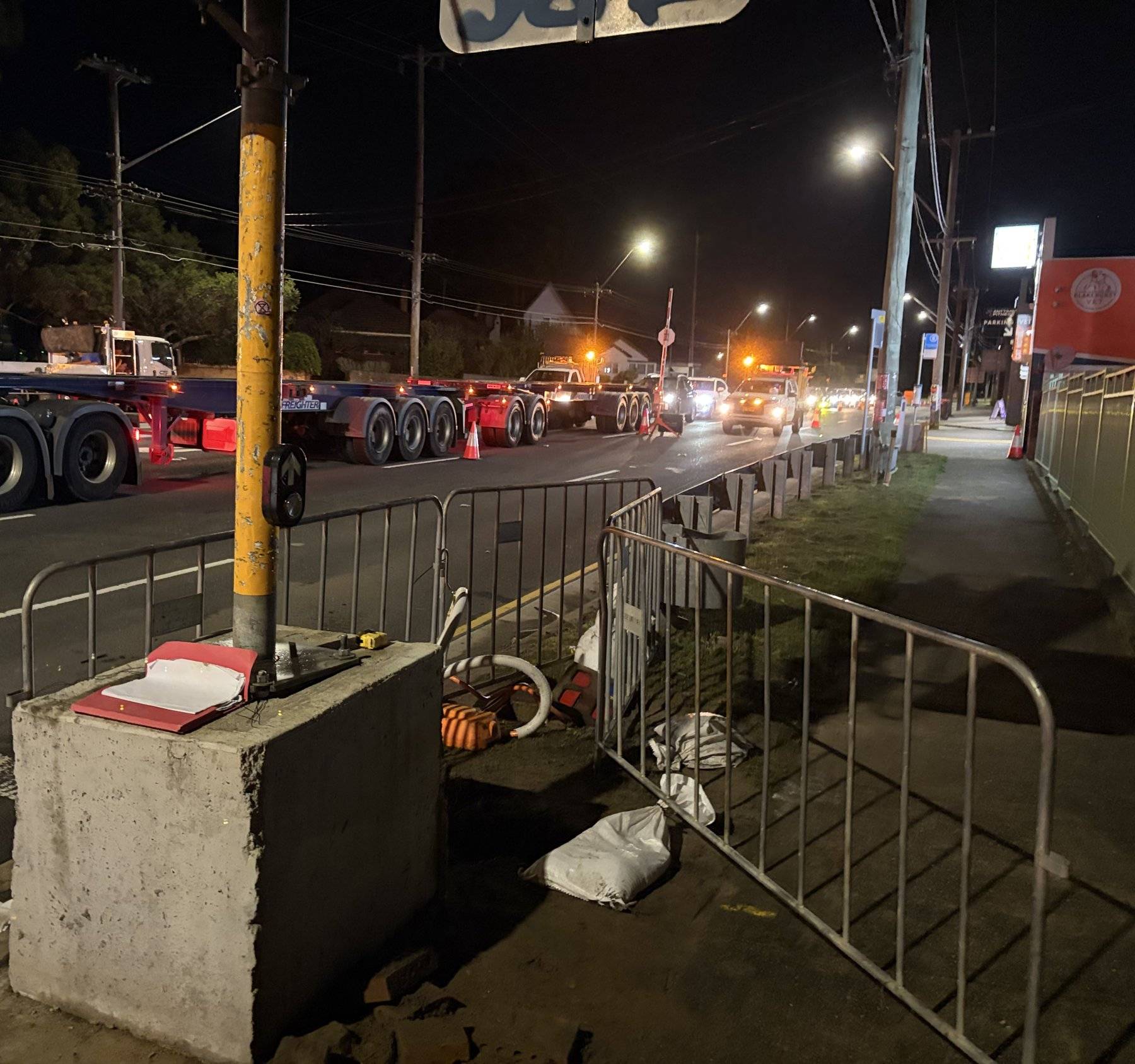 Signal pole footing excavation behind barriers at a closed intersection at night