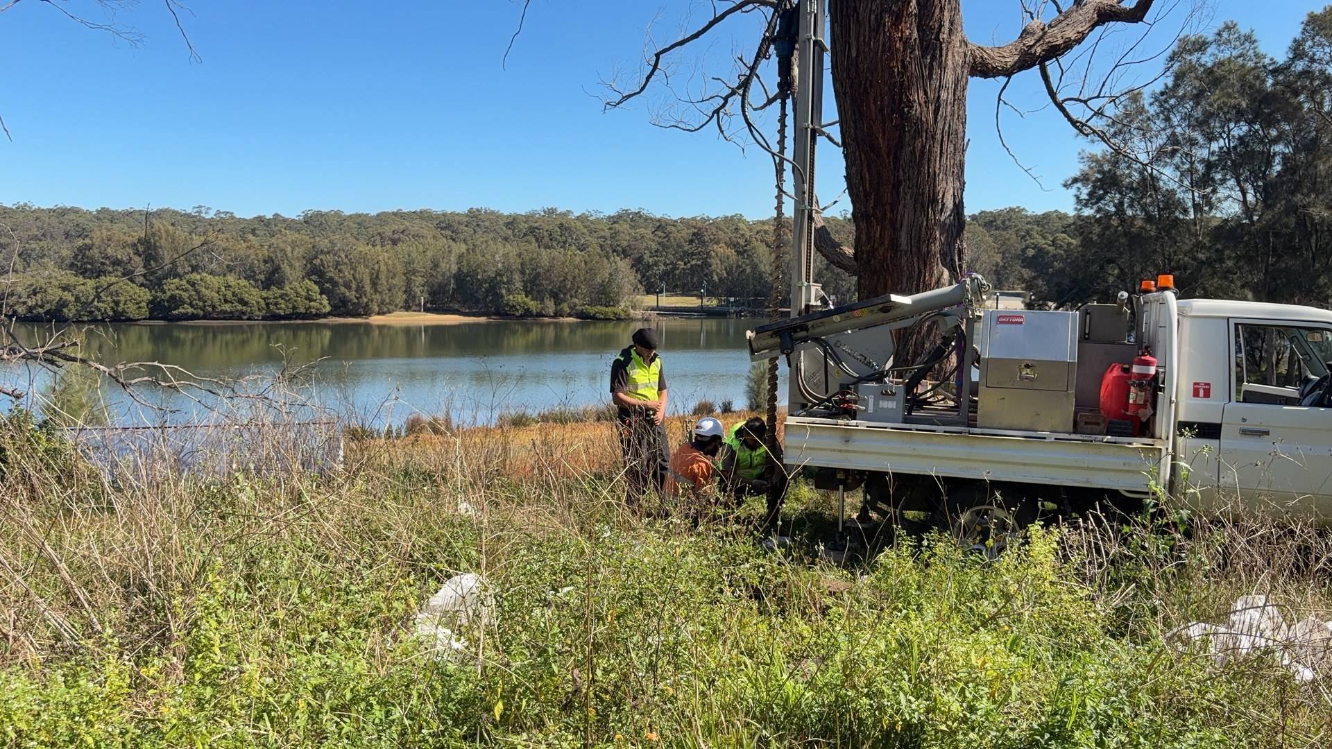 Drill rig and crew sampling low-lying ground beside a Sydney river