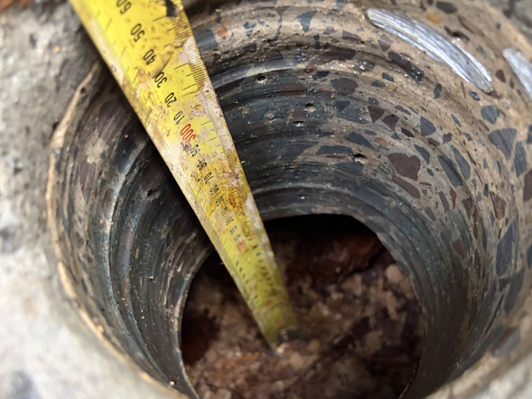 Tape measure checking depth down a cored hole through a slab