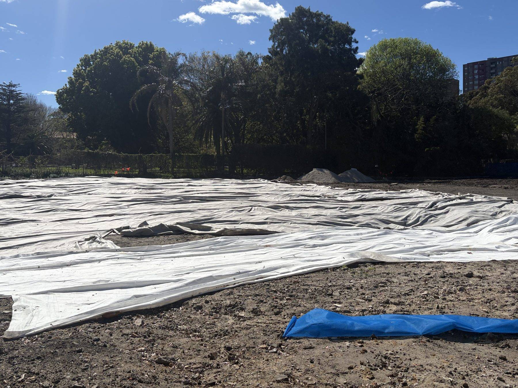 Geofabric capping laid over cleared ground on an inner-city Sydney site, with stockpiles waiting behind