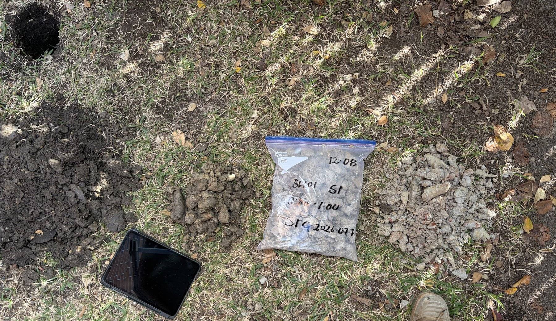 Labelled soil sample bag and field tablet during sampling for laboratory testing