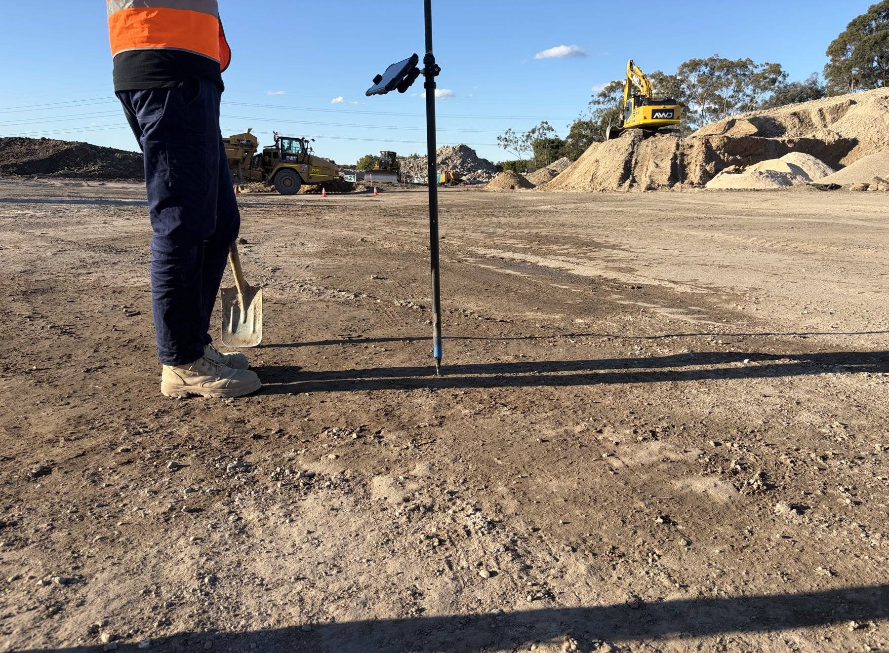 Level staff standing on a freshly graded pad during earthworks
