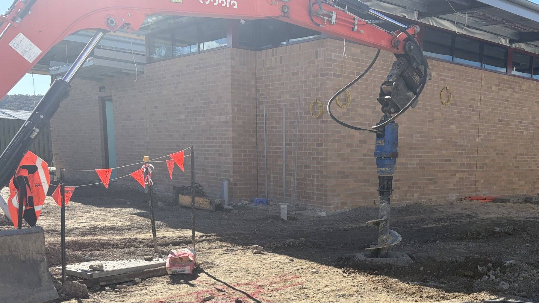 Piling rig working beside a brick building on a Sydney site