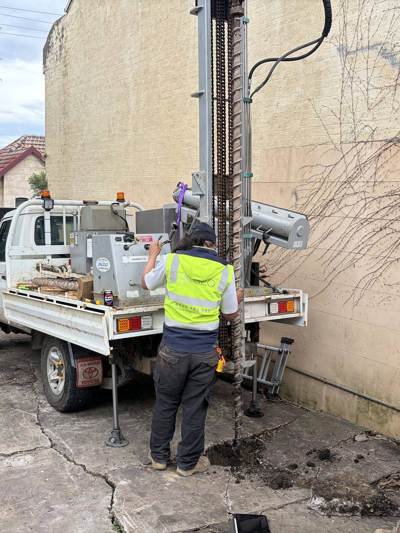 The SFGEO 4WD drill rig set up inside a narrow terrace courtyard in Enmore, mast up against the rendered wall