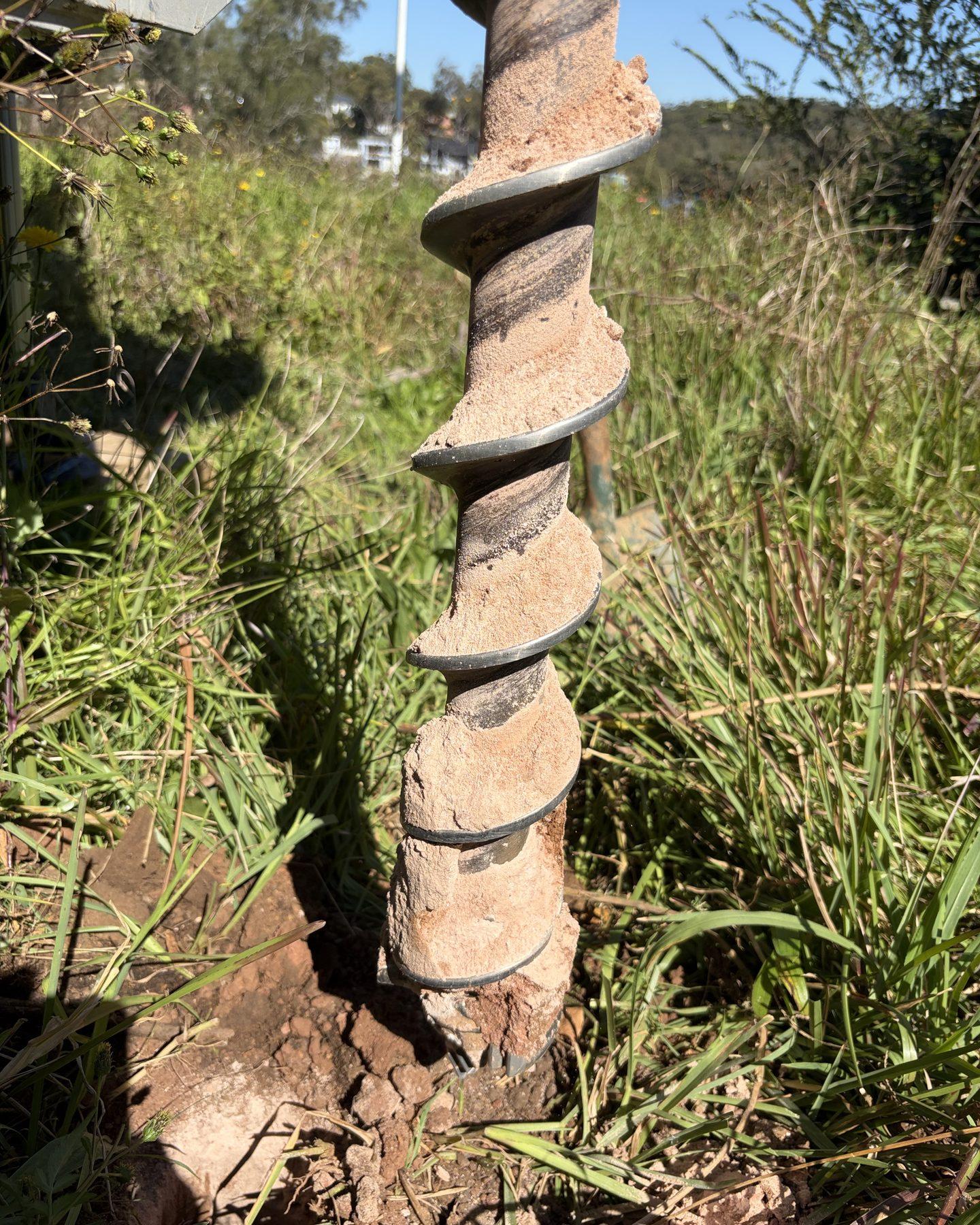 An auger flight lifted from a borehole, the soil profile held in sequence on its flights