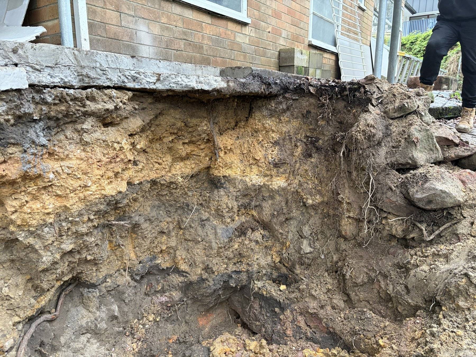 Undermined retaining wall face exposed during a geotechnical assessment